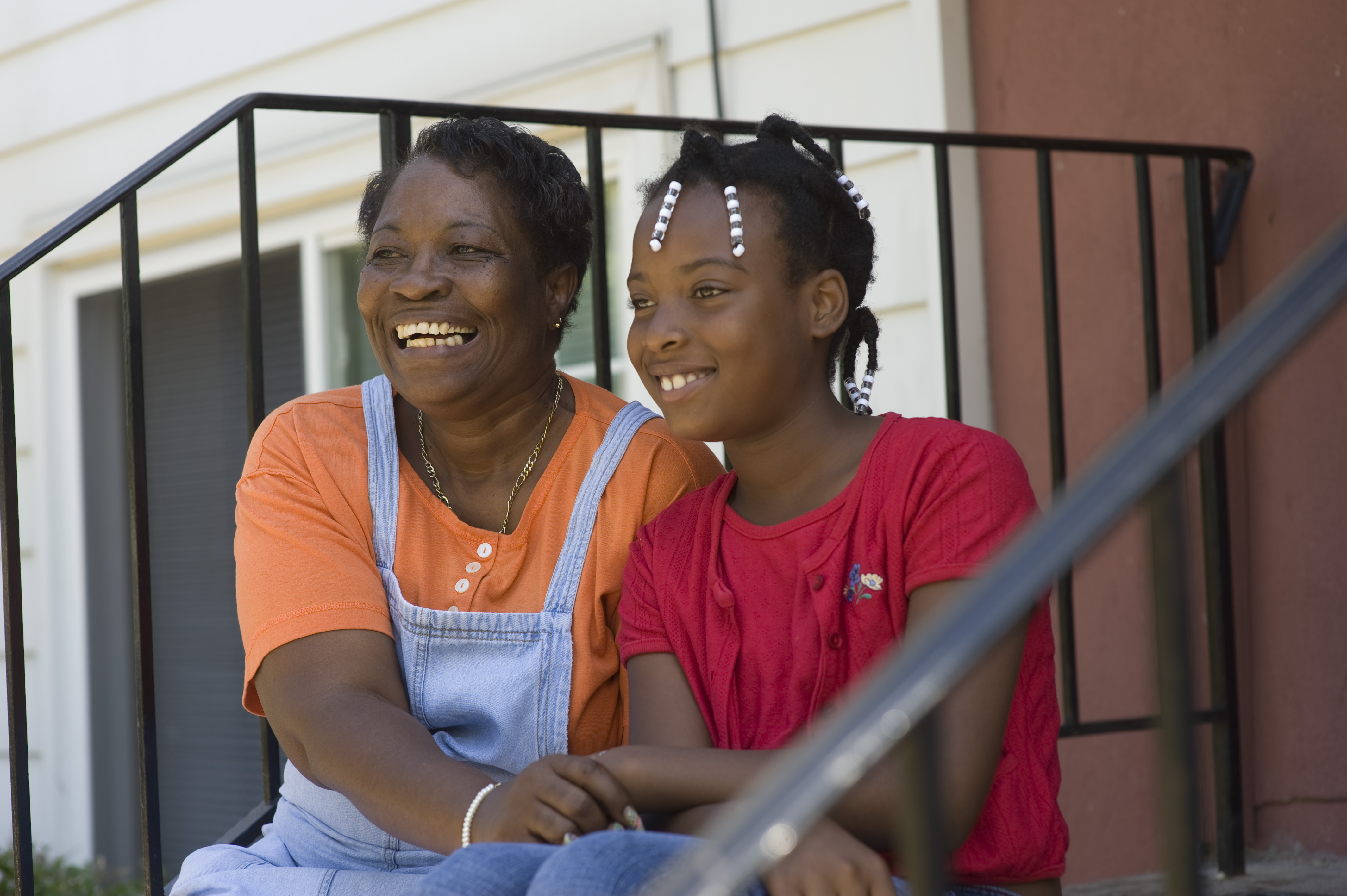 Woman and girl sitting on front steps with a black railing