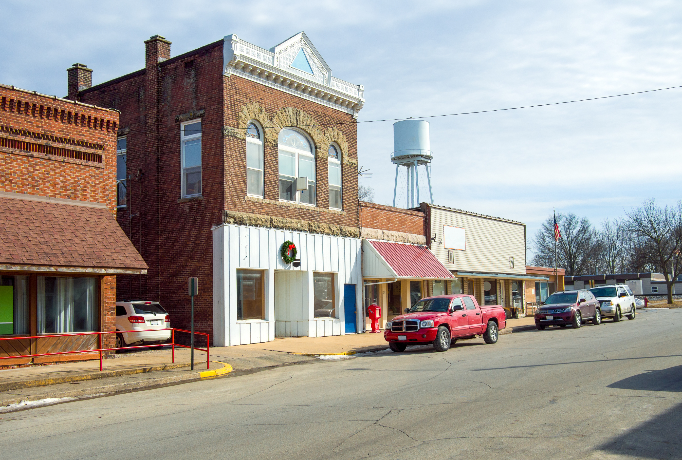 Storefronts lining a street with a water tower on the horizon