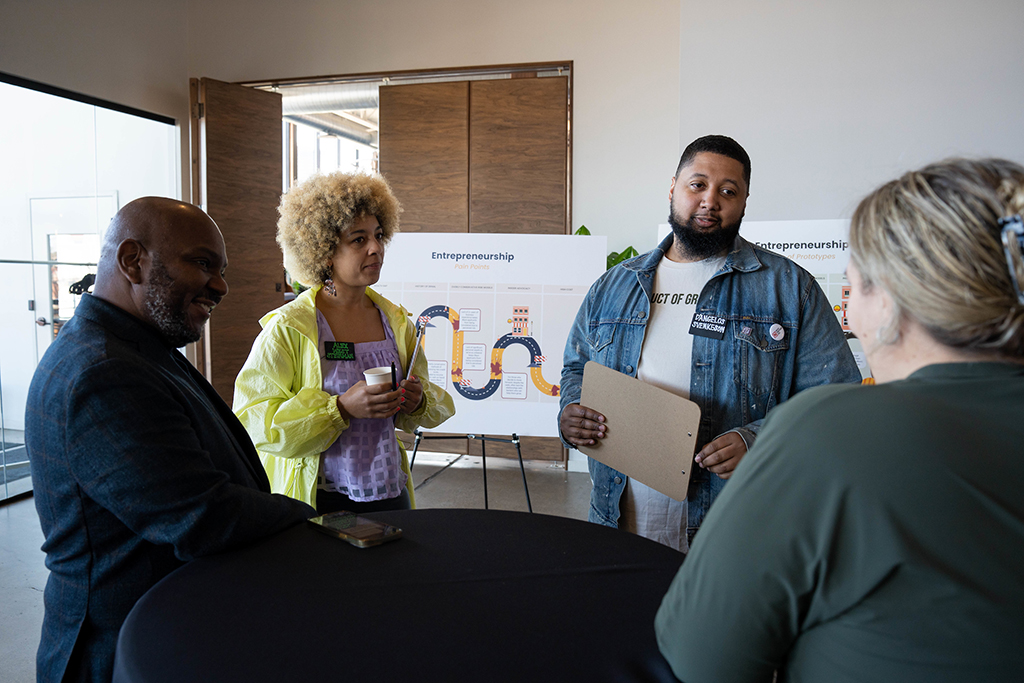 People_talking_in_front_of_a_poster_on_an_easel