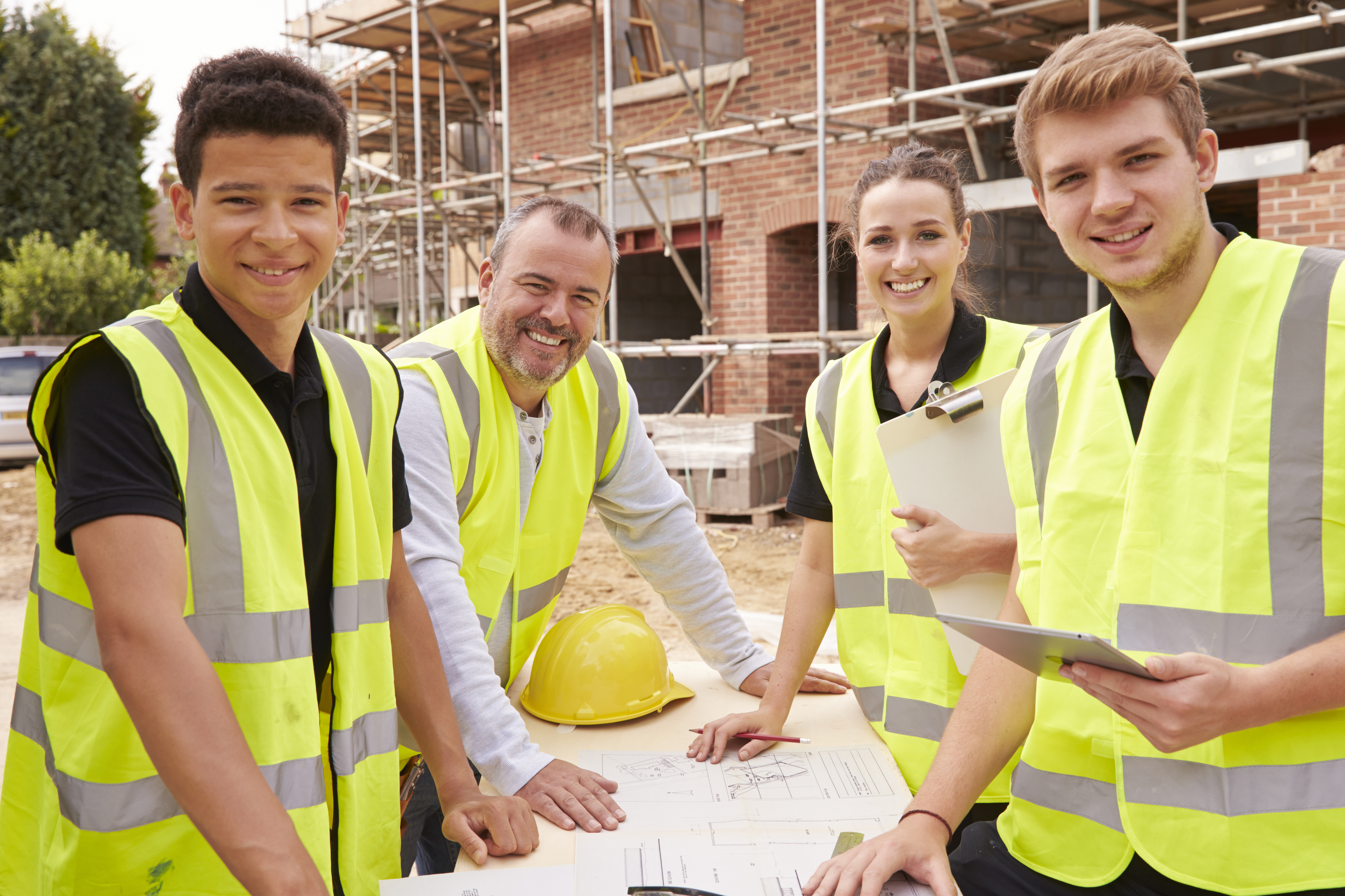 Three young people and an older mentor at a construction site